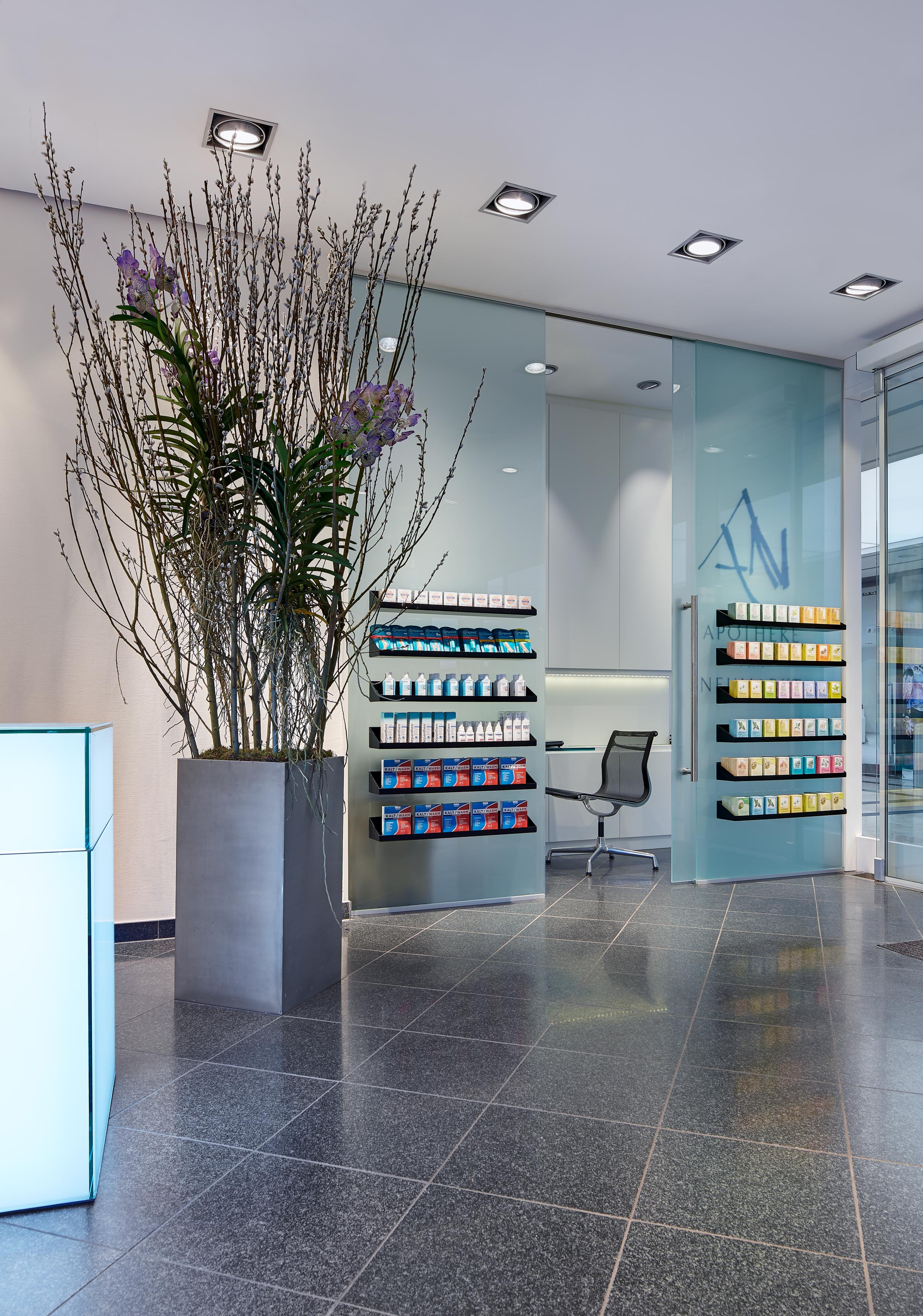 Diskreter Besprechungsbereich mit einer mattierten Glasschiebetür, bedruckt mit dem Apotheken-Logo und einem minimalistischen Arbeitsplatz