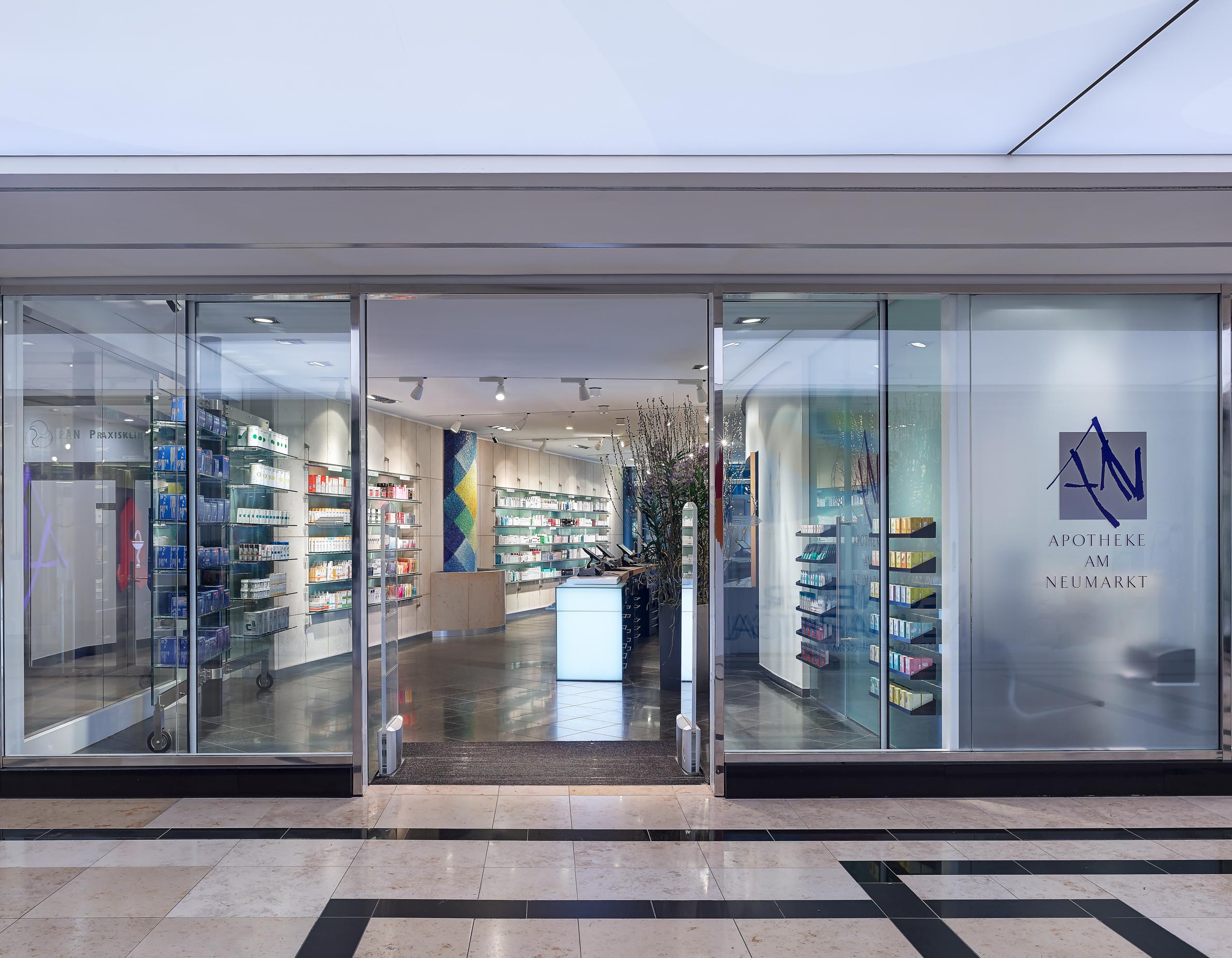 Transparente Portalfront der Apotheke am Neumarkt mit Blick aus der hellen Einkaufspassage der Neumarkt-Galerie