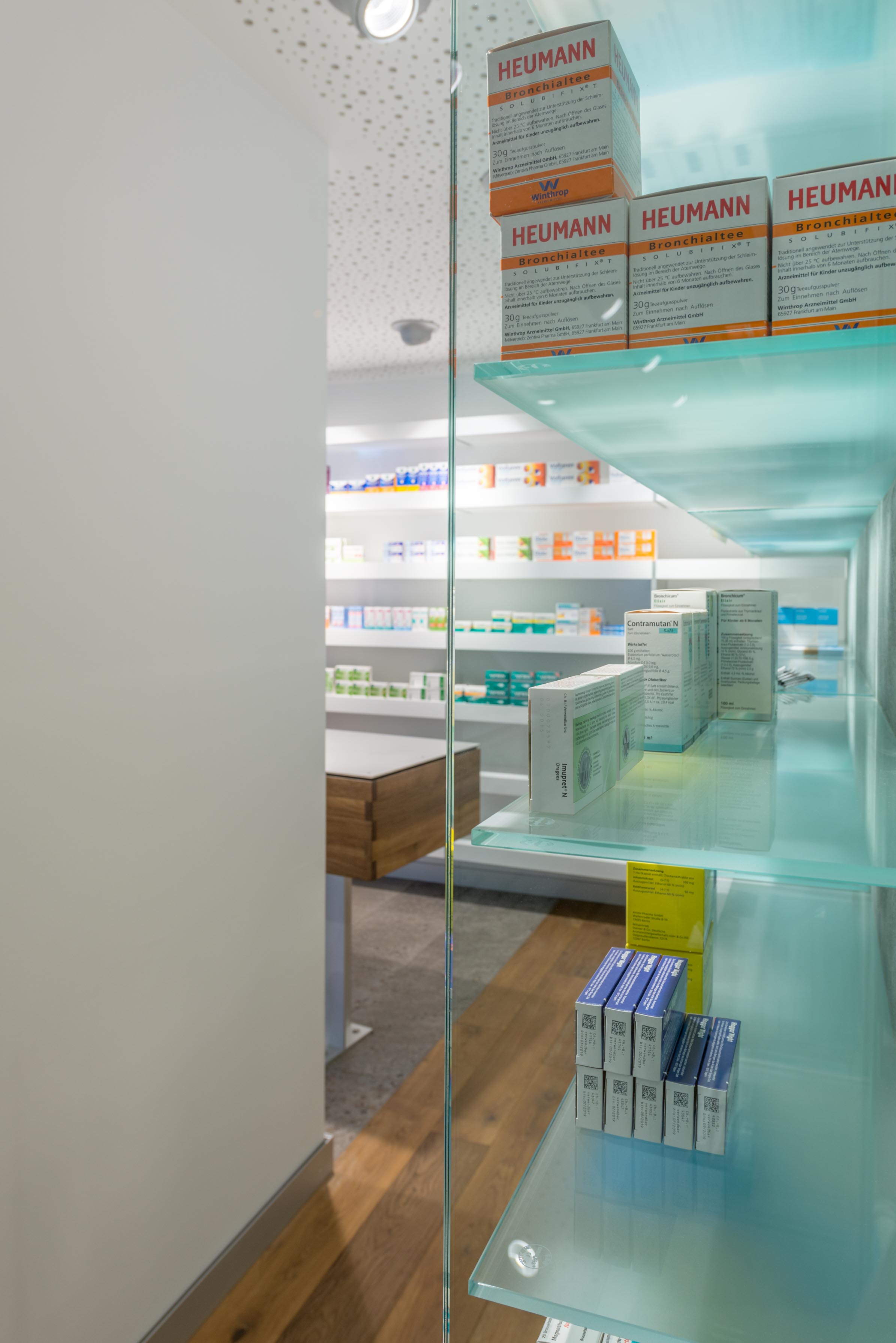 Perspektivischer Blick durch die grünlich gefärbten Glaselemente auf den rückwärtigen Apothekenbereich