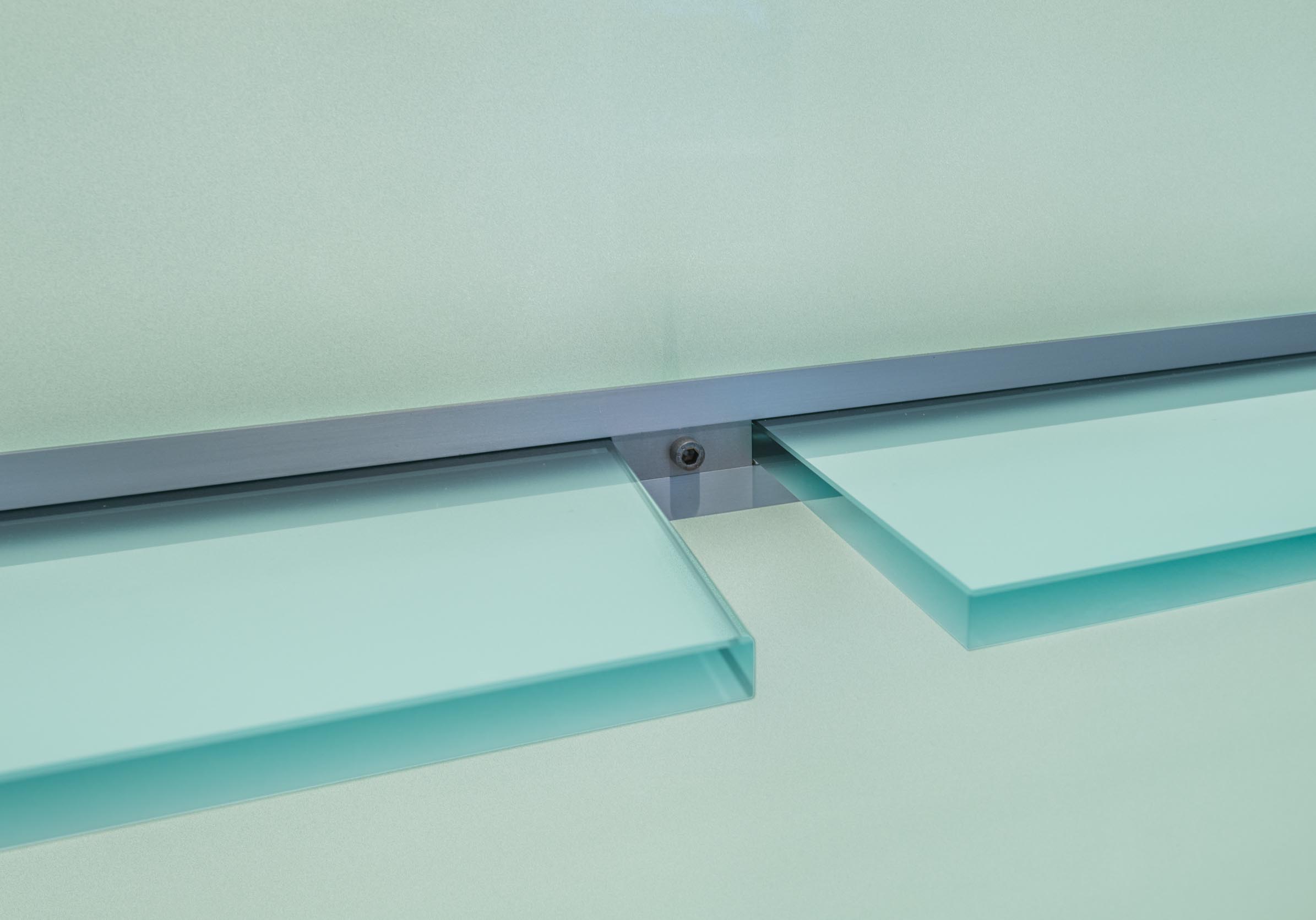 Detailaufnahme der bündigen Glasplatten-Halterung und Beschläge an der transluzenten Front des HV-Tisches